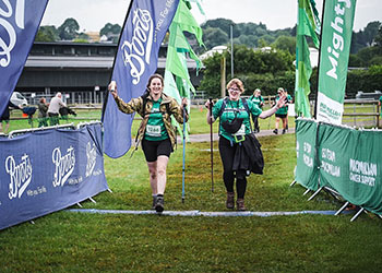 Two of the P & B trailblazers crossing the finish line holding walking poles