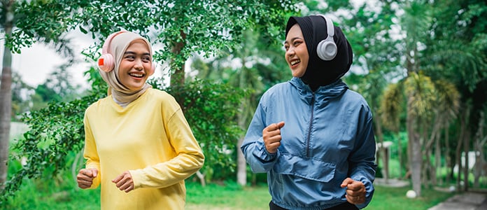 children wearing headphones running through the park