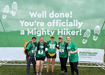 Team photo in front of a sign saying well done you are officially a Mighty Hiker